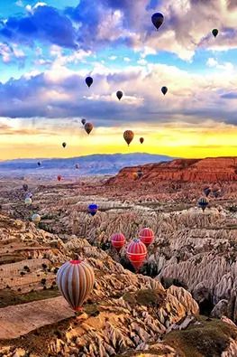 A hot air balloon floating in a sunset canyon